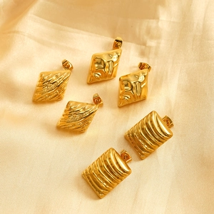 Golden textured geometric stainless steel stud earrings set on champagne satin fabric
