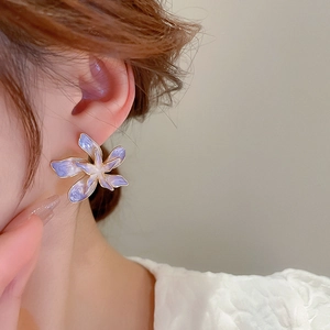 Vue rapprochée d'une boucle d'oreille fleur violette dégradée portée par un modèle
