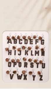 Macro detail of alphabet leather keychains with leopard print and plush pompoms
