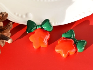 Close-up of festive red resin bell earrings with green bows for Christmas holiday decor