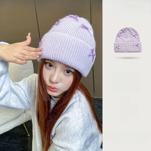Dettaglio della trama a maglia in pelo di coniglio e dei fiocchi viola sul cappello