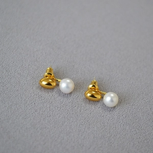 Close-up of gold-plated brass ear studs with natural freshwater pearls and silver needles