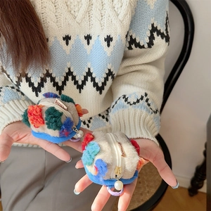 Dettaglio della pochette in peluche con motivi colorati e cerniera con perla