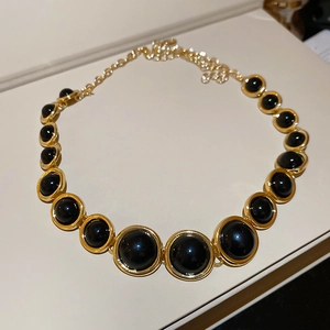 Detailed macro view of the gold necklace featuring large black resin round pendants
