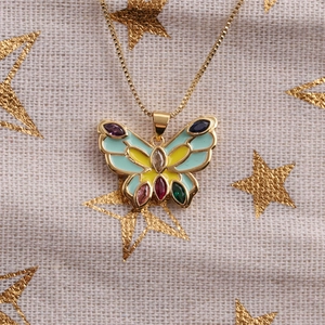 Gros plan du collier papillon doré avec cristaux multicolores et détails en émail bleu