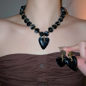 Detail of marble pattern acrylic heart necklace and earrings set worn by a model