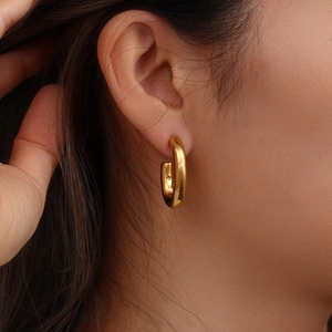 Close-up of golden hollow hoop earring on ear showcasing minimalist high-polish finish