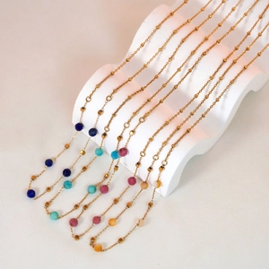 Minimalist gold stainless steel necklaces with colorful square and round beads on white stand