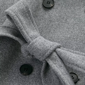 Gray wool blend double-breasted coat detail featuring black buttons and tie-waist belt