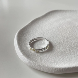 Close-up of a 925 silver irregular ring set with yellow cubic zirconia on white ceramic