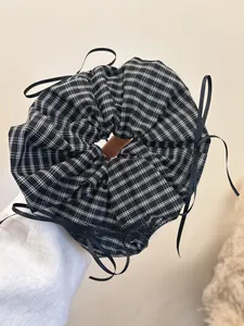 Close-up of black and white plaid scrunchie with long black ribbon tie detail