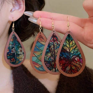 Detailed macro view of teardrop wooden earrings featuring colorful mosaic patterns