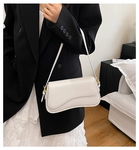Fashionable cream white faux leather shoulder bag styled in a minimalist casual street look