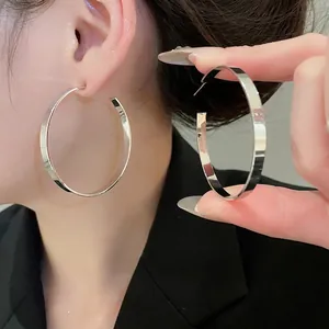 Polished silver large hoop earrings with flat surface design on a female model