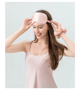 Detail of pink 22 momme silk sleep eye mask set worn by model with matching silk nightgown