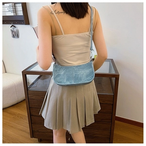 Model wearing a blue vintage style shoulder bag with metallic finish and punk rivet details