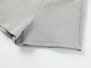 Detailed close-up of gray knitted fabric texture and double-stitch hem on yoga shorts