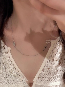 Gros plan d'un collier argenté avec pendentif croix et médaille sur une chaîne perlée