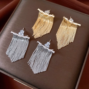 Détail de boucles d'oreilles à pompons dorées et argentées serties de zircons