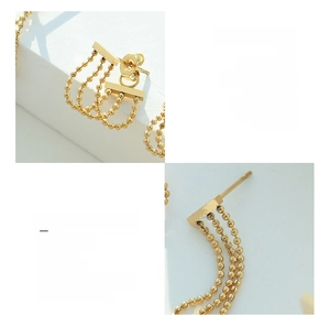 Vue macro détaillée de boucles d'oreilles pompons en acier titane plaqué or 18 carats avec lustre