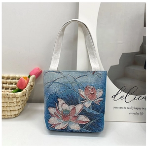 Detailed view of blue ethnic canvas bag featuring pink lotus embroidery and white handles