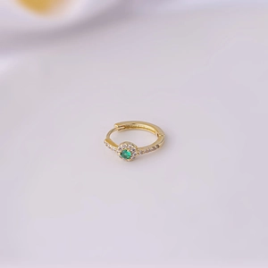 Macro shot of gold-plated hoop earring with emerald center stone and zirconia accents