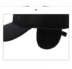 Detail view of winter baseball cap with ear flaps and metal shield emblem on black fabric