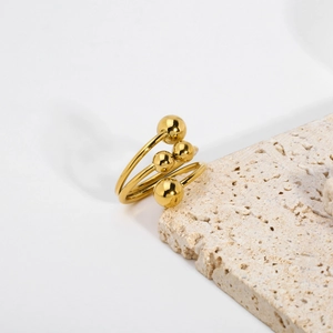 Anello a spirale dorato minimalista a più strati con perle lucide su supporto in pietra