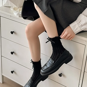 Black lace ruffle socks with bow detail worn with platform loafers on model legs