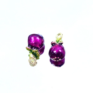 Detailed close-up of purple fruit enamel charms with green leaves and golden loop rings