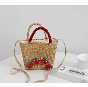 Détail du sac en paille avec fraises au crochet et poignées en velours rouge élégant