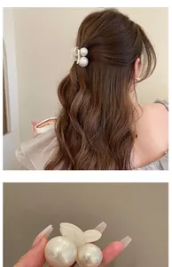 Detail shot of elegant hair clip featuring large pearls and translucent butterfly decor