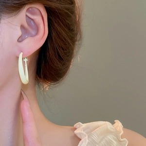 Close-up of minimalist pale yellow hoop earring on model showing sleek matte finish texture
