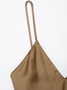 Detail of brown satin slip dress showing thin straps and V-neckline on white backdrop