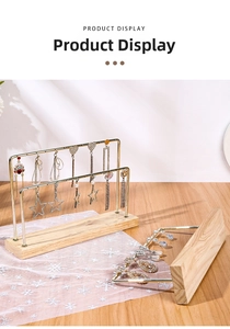 Detail of gold metal earring stand with wooden base showing jewelry storage holes
