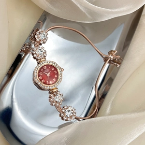 Elegant rose gold women's watch with red dial and rhinestone detail on silk background