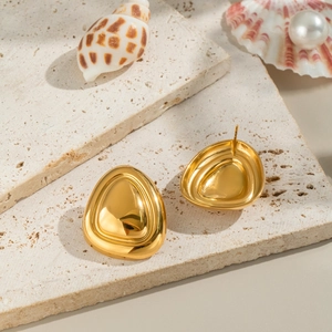 Detailed view of gold shell earrings on stone with pearls for a beach vacation look