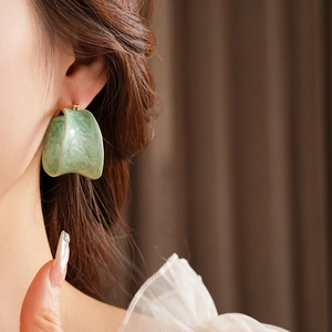 Detail of green resin hoop earrings with marble texture worn by a model