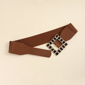 Detail of a brown elastic wide belt featuring a square buckle with black geometric gems