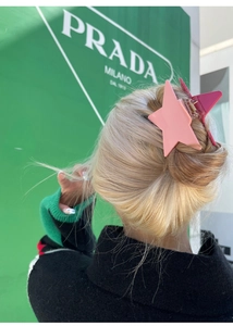 Detail showing a pink star-shaped hair claw clip on a stylish bun hairstyle
