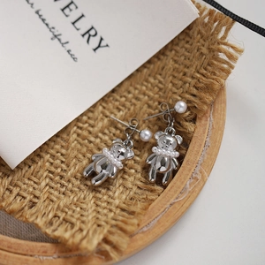 Silver bear stud earrings with pearls on a rustic linen background in macro view