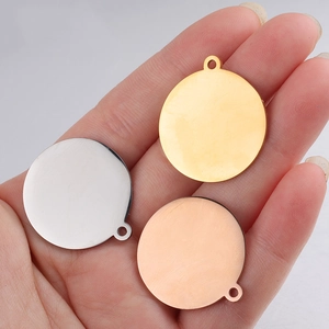 Close-up of gold, silver, and rose gold round metal pendants held in hand for scale