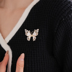 Detail of 18k gold plated butterfly brooch with white shell and crystals on model