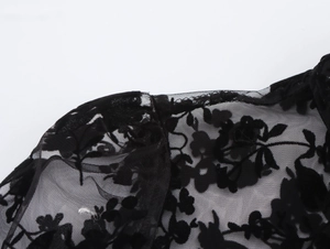 Detail of sheer black mesh fabric with floral flocking and delicate lace neck design