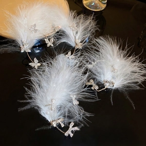 Elegant white feather ear cuff with rhinestone butterflies on a reflective black background