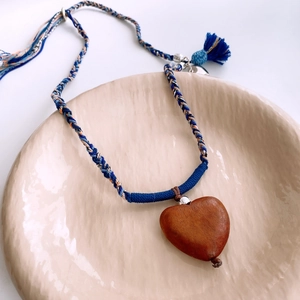 Detail of wooden heart pendant with multi-color braided rope and blue tassel decoration