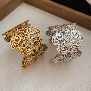 Macro detail of vintage hollow flower carvings on gold and silver open bangle bracelets