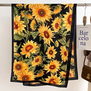 Detail of vibrant sunflower print on soft black silk scarf with high-quality finished edges