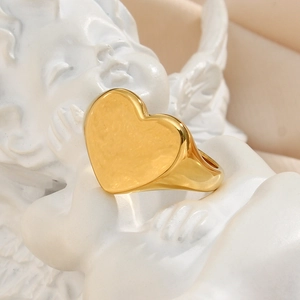 Polished 18K gold plated stainless steel heart signet ring on a white angel statue