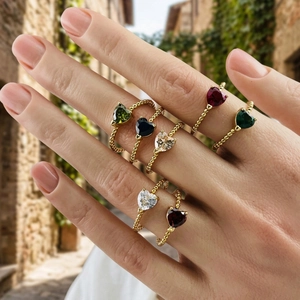 Close-up of gold beaded rings with colorful heart-shaped gemstones worn by a model